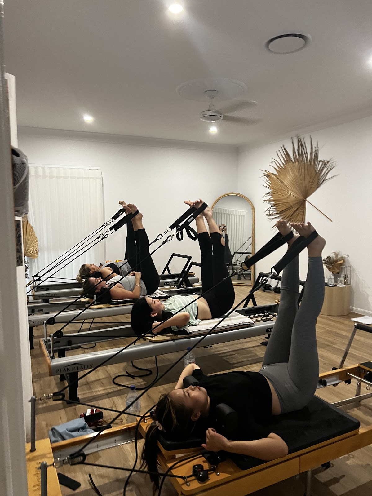 A class of four women on reformers at Hustle Reformer Pilates Co in Robina